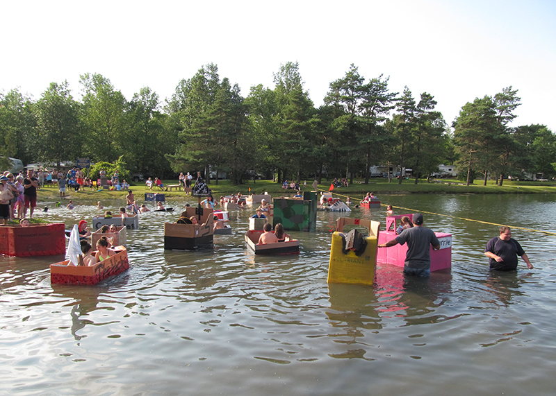 campers sailing homemade cardboard boats in the pond